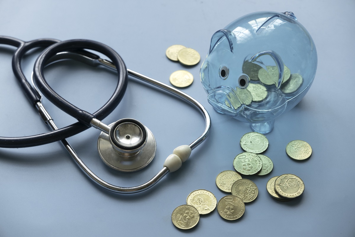 a stethoscope next to a piggy bank and coins